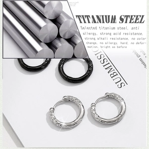 Detail of titanium steel hoop earrings with engraved dragon patterns in black and silver