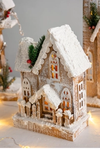 Detailed view of glowing wooden Christmas cottage with snow texture and LED light