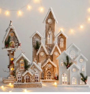 Close-up of lighted wooden Christmas houses with snowy roofs and warm festive LED lights