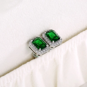Macro shot of emerald cut green zircon earrings with silver metal pave setting
