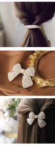 Detail of gold-plated leaf and bow hair clips with white pearls on elegant silk fabric