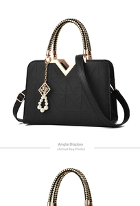 Detail showing the geometric triangular texture and V-shaped gold metal clasp on a black bag
