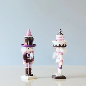 Detailed view of pink Christmas nutcracker wooden figures with cake and teacup hats
