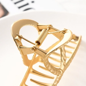 Detailed close-up of golden alloy hair claw clip with anti-slip texture and spring mechanism