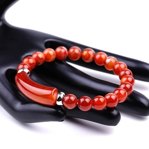 Macro shot of natural red agate beads and silver tube bracelet on a black hand model