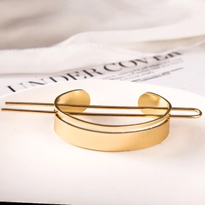 Elegant gold metal hair bun cuff with a smooth pin displayed on white decorative plate