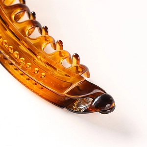 Detail of amber translucent hair claw clip showing polished teeth and hinge structure