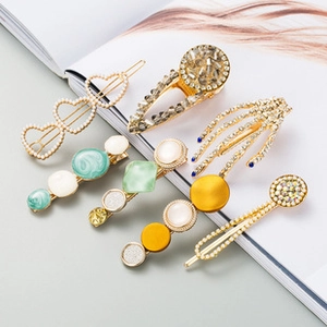 Platte lay-set van vintage gouden haarklemmen met parels en kristallen op gids