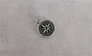Detailed macro view of vintage silver compass pendant with NESW engraving and star