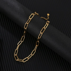 Close-up of golden paperclip chain necklace with lobster clasp on black background
