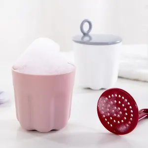 Detail view of pink facial cleanser foaming cup with rich foam and plastic handle
