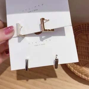 Minimalist geometric bar stud earrings in gold and silver finish shown on white card