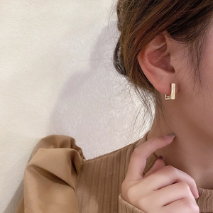 Close-up of minimalist gold plated geometric rectangular hoop earrings on female model