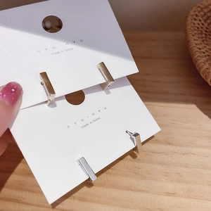 Close-up of minimalist gold and silver geometric rectangular hoop earrings on display card