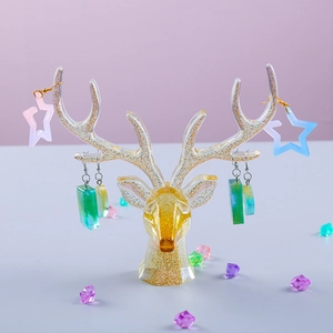 Detailed view of antler jewelry stand in gold glitter resin showing hanging earrings