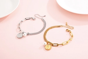 Detail of coin pendant bracelets featuring gold and silver plating with pearl accents