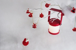 Close-up of a red portable lantern lamp with foldable shade and a festive knit doll decor