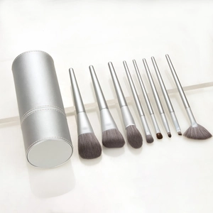 Detail view of 9-piece silver makeup brush set and matching cylindrical leather storage tube
