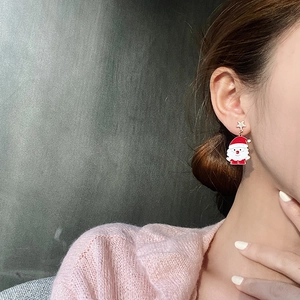 Close-up of Santa Claus festive earring with a gold star stud and enamel drop pendant