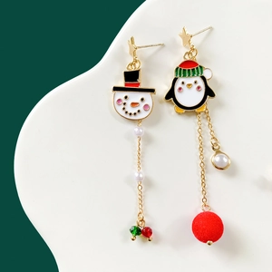 Detail of asymmetric Christmas earrings with snowman, penguin charms and red pompom