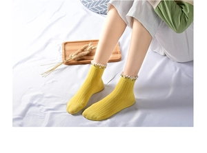 Detail of yellow cotton crew socks with white lace trim and faux pearl embellishments
