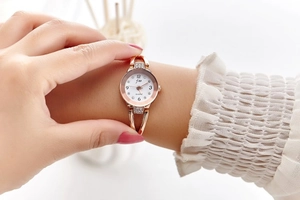 Detail of elegant rose gold steel ladies watch with rhinestone-studded white dial on wrist
