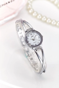 Detailed macro of a silver quartz watch with a diamond bezel and pearl necklace