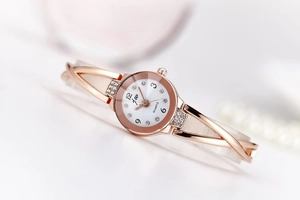 Close-up of rose gold watch dial with crystals and white ceramic link bracelet band