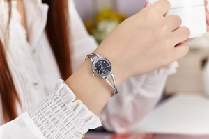 Close-up of a stylish silver bangle watch with a black diamond-set dial worn on a wrist