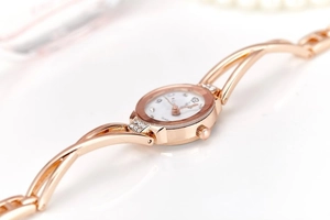 Detailed macro of rose gold bracelet watch featuring a white crystal-encrusted dial