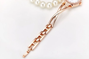 Macro shot of rose gold steel watch strap links and folding clasp with pearl background