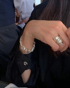 Detailed view of layered silver leaf ring and baroque pearl bracelet on model hand