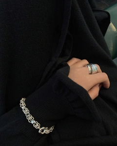 Detail of 925 sterling silver wide leaf ring and textured bracelet on a dark knit background