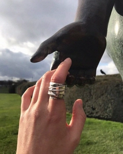 Artistic detail of a wide textured 925 sterling silver leaf ring worn on hand outdoors