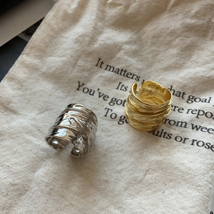 Detailed view of wide leaf rings with crinkled texture in gold and silver finish