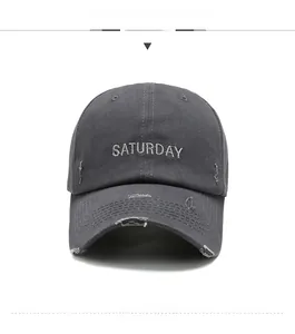 Détail d'une casquette en coton gris foncé vieilli avec broderie Saturday et bords déchirés