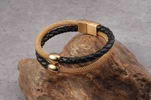 Macro detail of double-layer black braided leather and gold mesh bracelet on rock