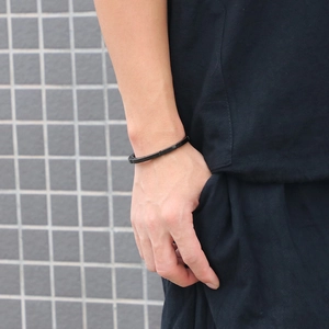 Minimalist black open cuff bracelet for men shown on wrist in a clean urban setting