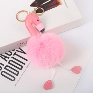 Detail of pink faux fur flamingo keychain with gold lobster clasp on white books