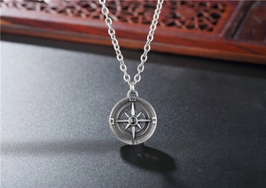 Detailed close-up of vintage silver compass pendant with star and cardinal directions