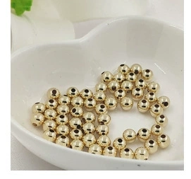 Close-up of 14K gold plated daisy spacer beads in a white heart-shaped ceramic bowl
