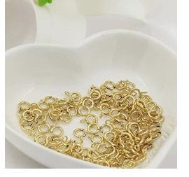 Golden spring ring clasps for jewelry making displayed in a white heart-shaped ceramic bowl
