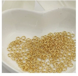 Macro shot of 14K gold-plated metal jump rings for DIY jewelry making in a heart bowl