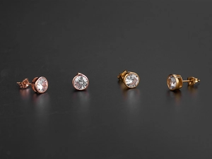 Gros plan de boucles d'oreilles dorées et or rose avec zircons sur fond noir élégant