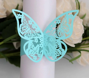 Macro shot of light blue laser-cut butterfly napkin ring with intricate floral patterns