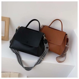 Detail of minimalist leather handbag with wide geometric pattern strap on white steps
