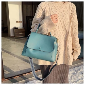 Blue trapezoid leather handbag with woven patterned strap and round decorative buckle