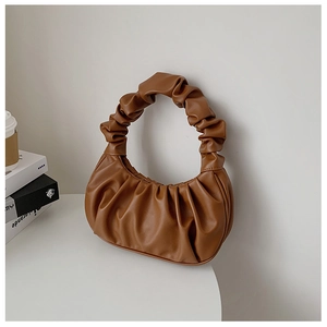 Close-up of brown ruched handbag showing soft faux leather texture and elegant pleats