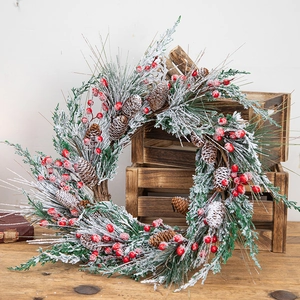 Classic Christmas wreath with red berries, pine cones and snow flocking on wooden crate