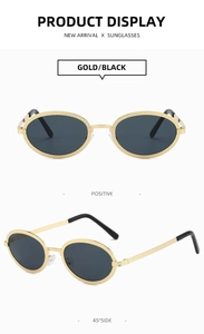 Close-up of gold oval sunglasses with black lenses showing textured metal frame details